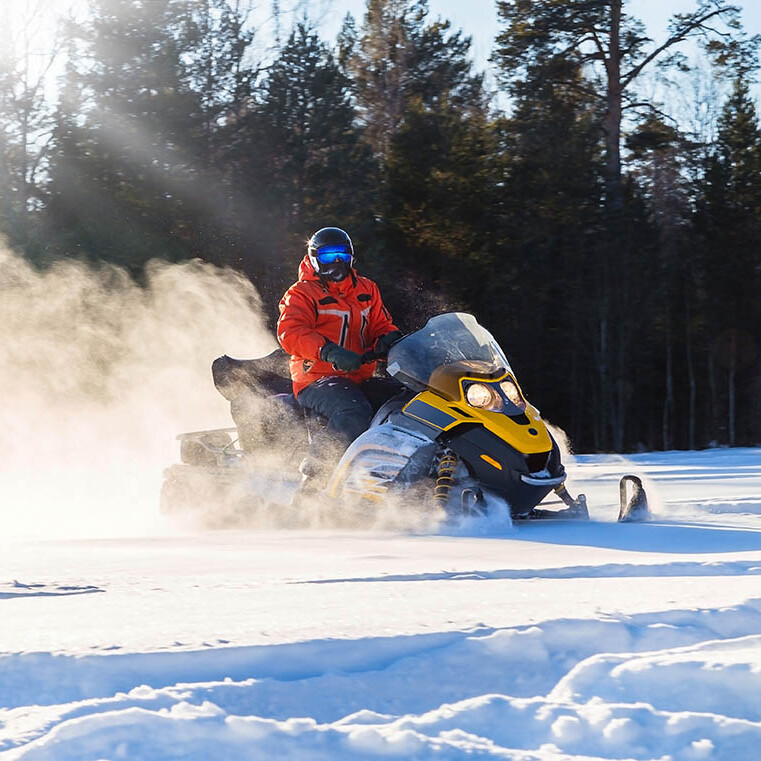 Team riding snowmobiles through the winter forest on a MICE trip in Rovaniemi