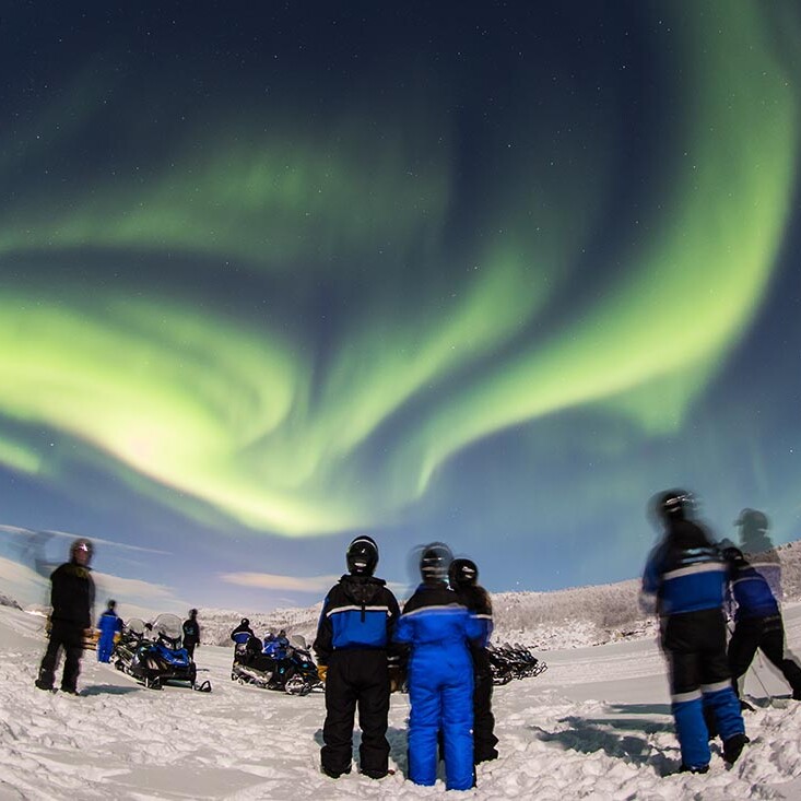 Business group participating in an outdoor snowmobile team building activity in Lapland